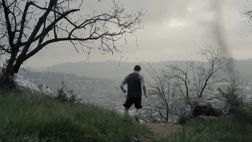 A man is jogging on a dirt trail under cloudy skies