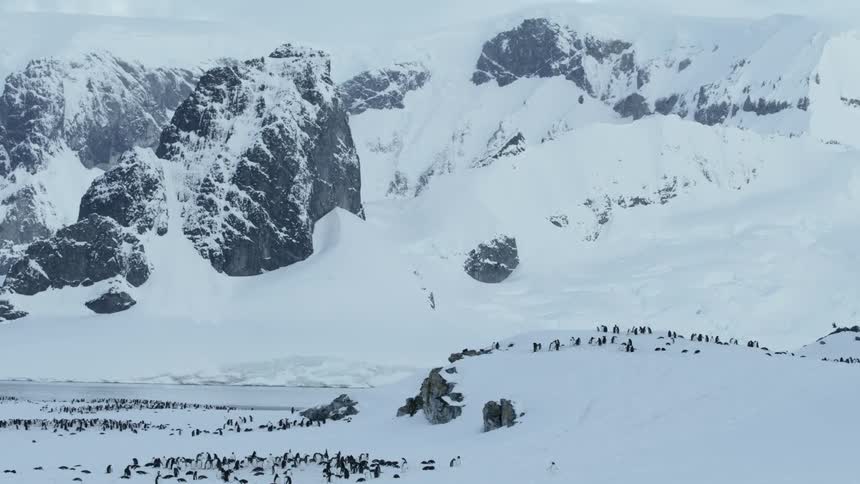 Snowy mountains sit under a cloudy sky