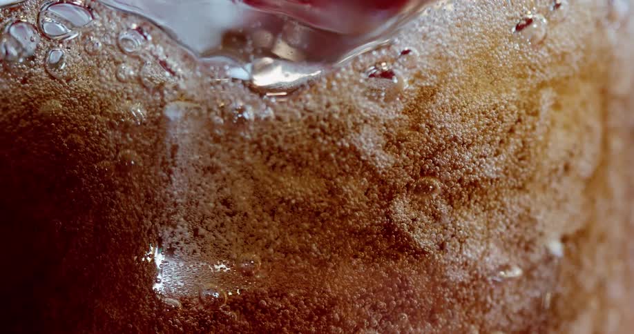 A carbonated beverage bubbles in a glass