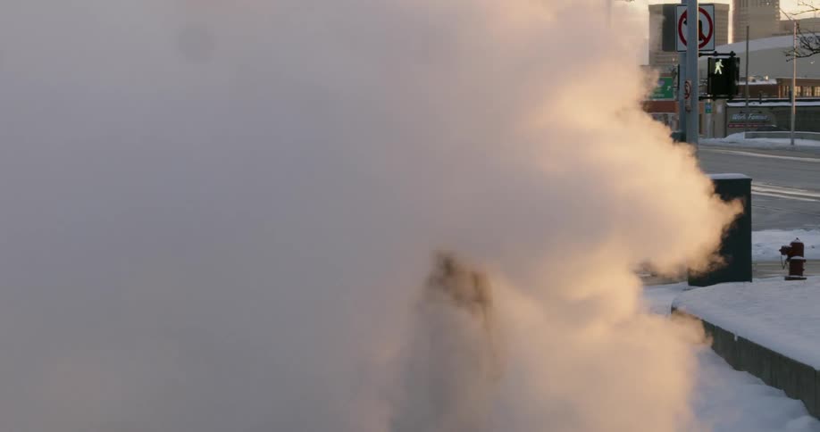 A man dances in steam by the street