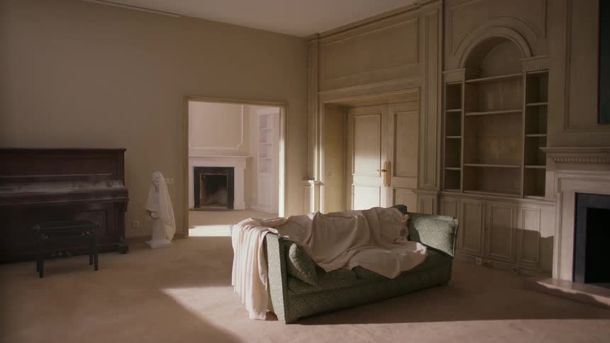 Sun shines on sheet covered furniture in a room