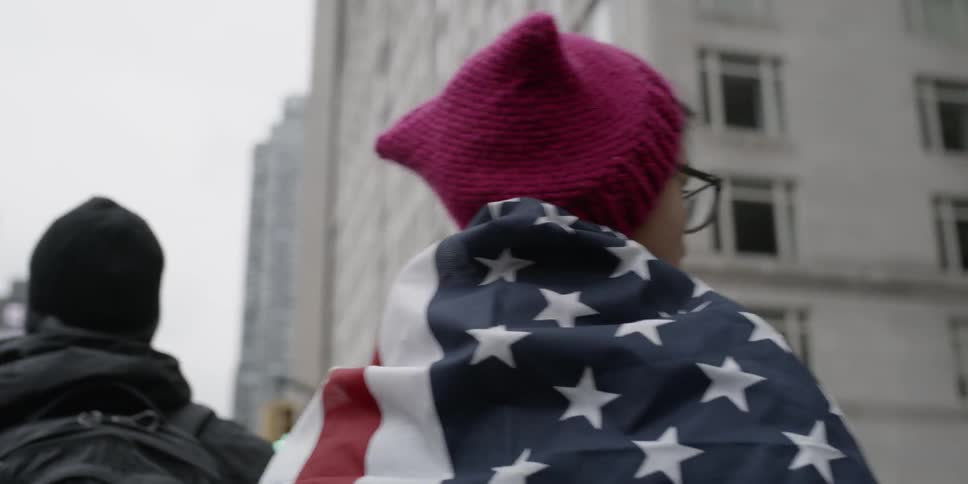 Person wears an American flag as they walk near a building