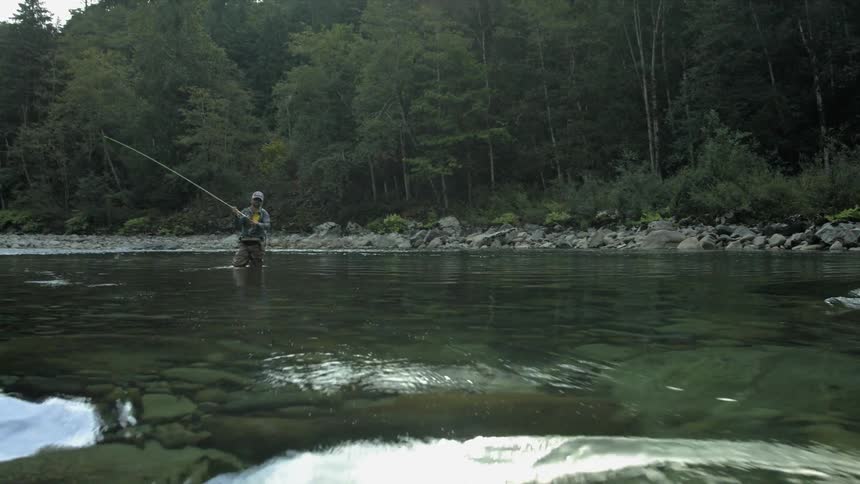 A man fly fishes in a stream