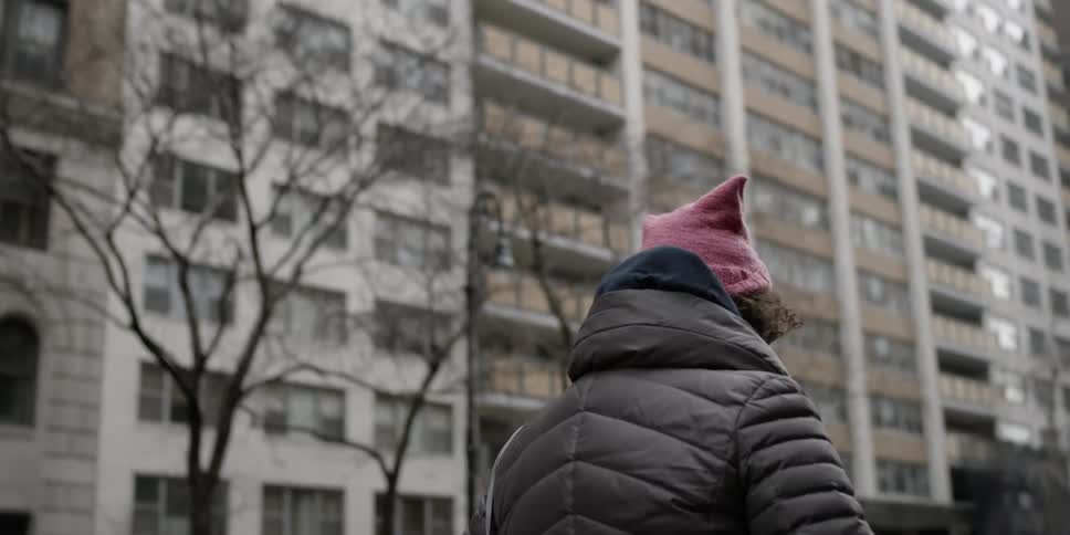 Woman walking outside in the city near tall buildings