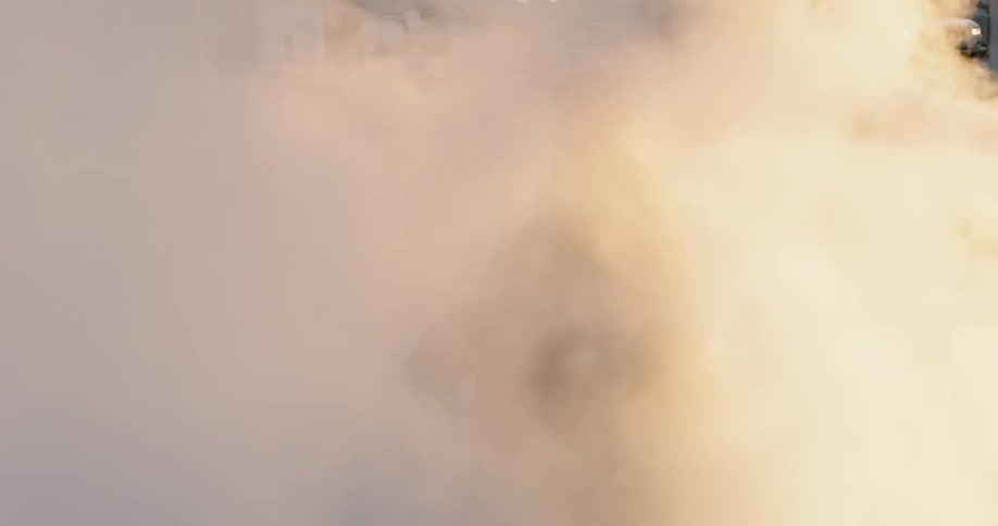A man dances in steam by the street