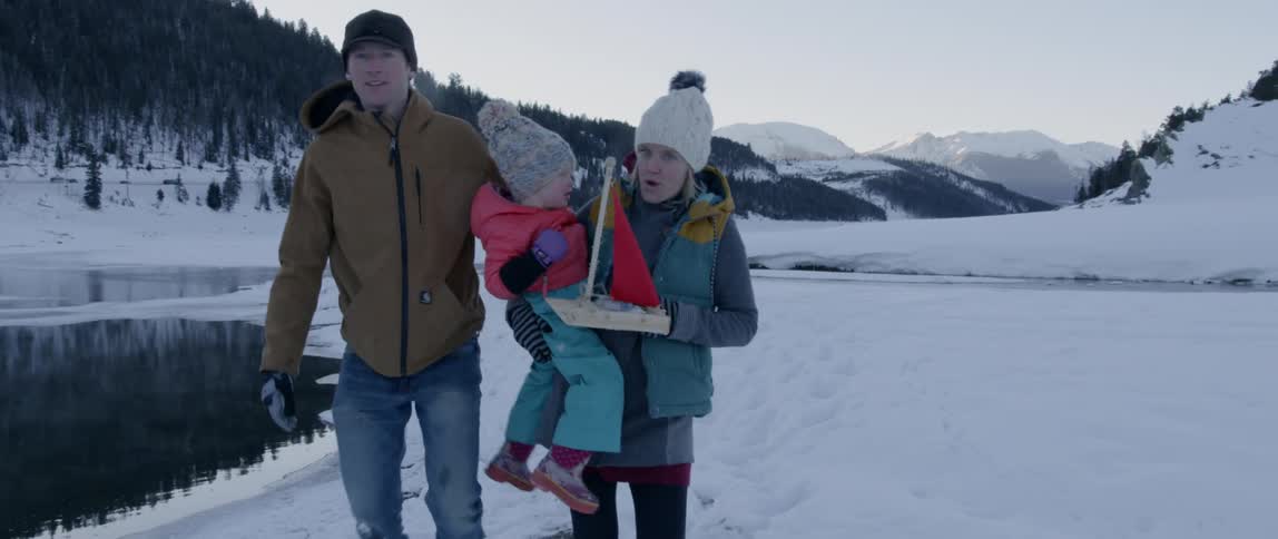 Woman carries a toddler as she walks with a man in the snow