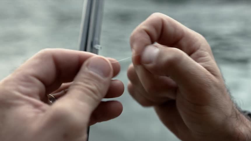 A man ties a hook to a fishing line