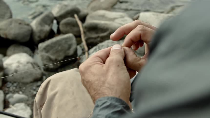 A man ties fishing line to attach a lure