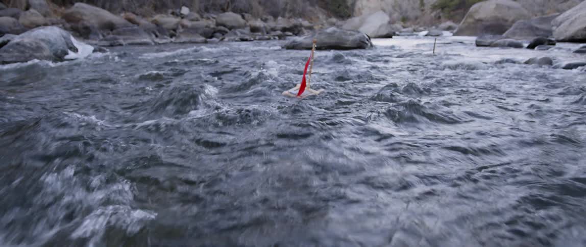 Toy boats are drifting down a rushing stream in daylight