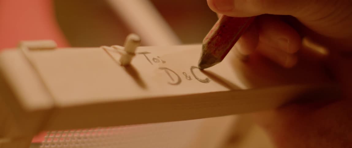 A person is writing a note on the frame of an item