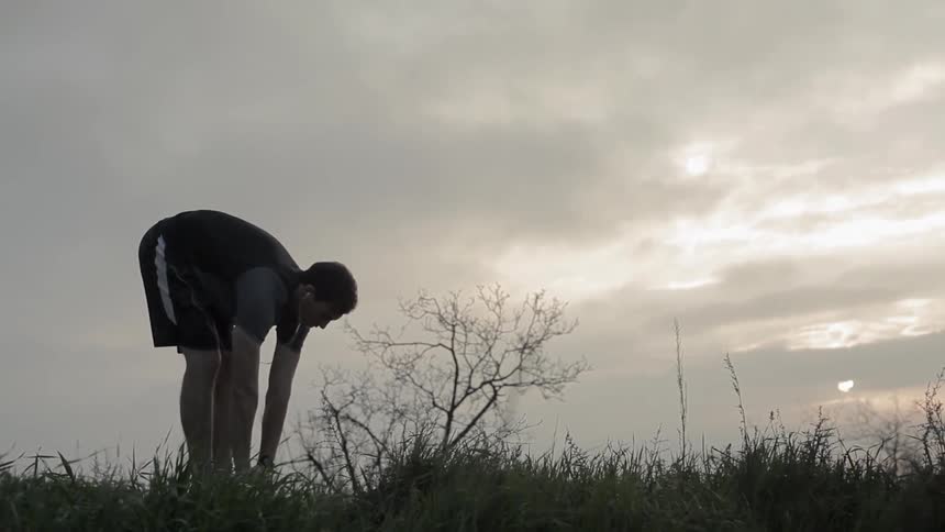 A man is stretching outside on a cloudy day