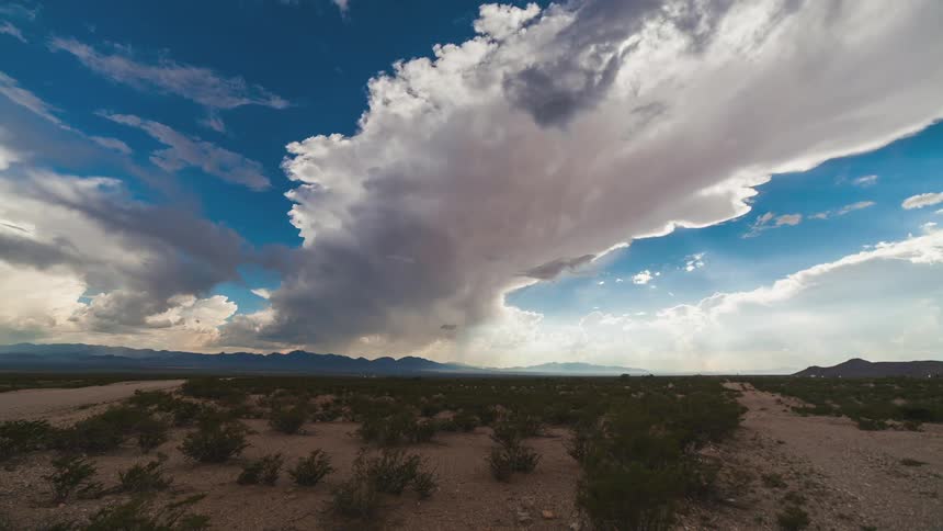 Traffic zips by on a rural road as clouds move over a desert