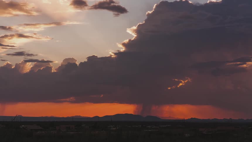 Dense clouds block sunlight over a mountain range and turn the sky orange