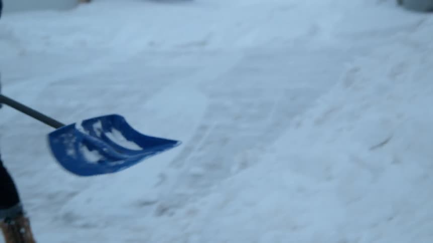 Woman shovels snow and tosses it aside