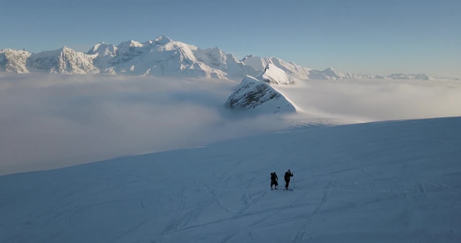 Two people cross country ski on a snowy field