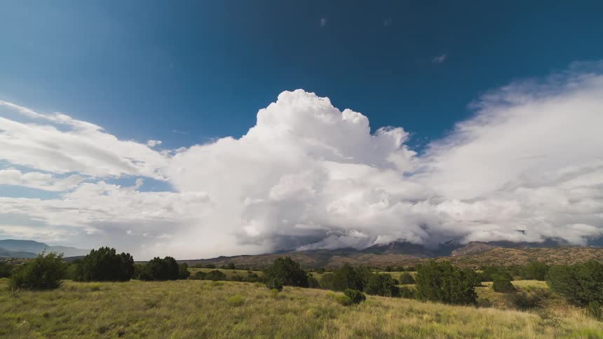 Clouds float above rolling hills in bright blue skies