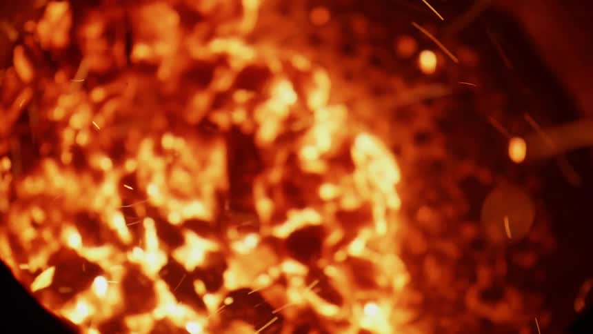 Sparks and ash swirl as fire is burning up some organic matter