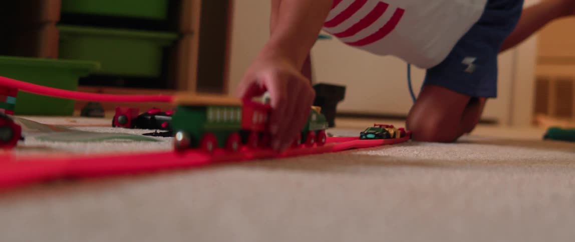 A young boy plays with toy cars and trains