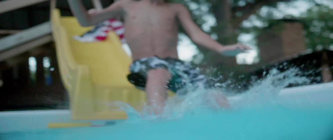 A boy slides down a water slide into a pool