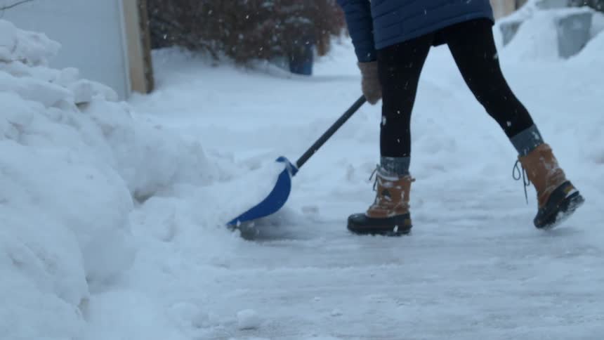 A woman shovels snow