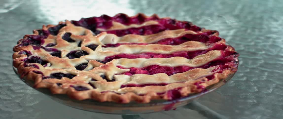 A berry pie sits on a glass table