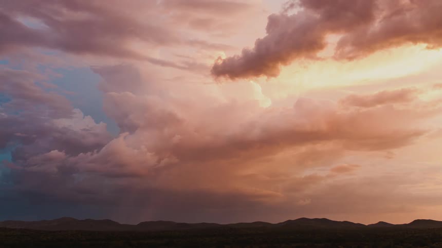 A desert with mountains in the background with the sky and clouds up above
