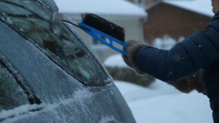 A person scrapes the ice off an suv window