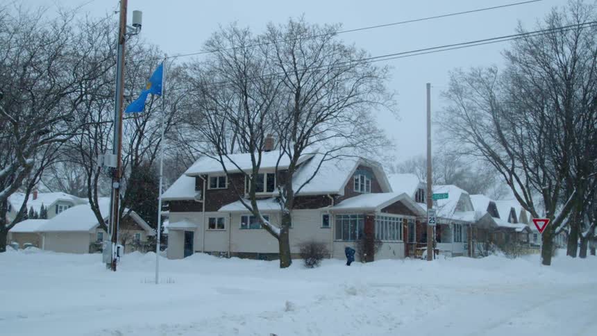 Blue flag blows in the snowy wind in a quiet neighborhood
