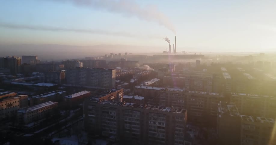 The sun sets over snowy city buildings
