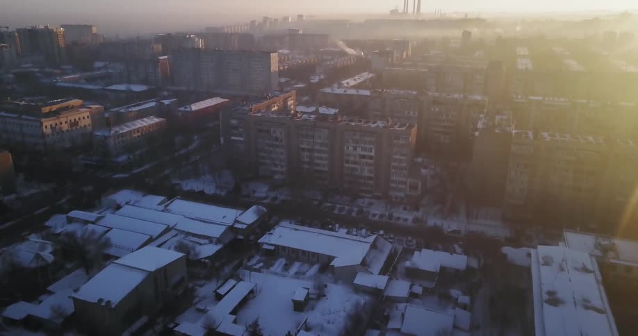Snow covers city buildings at sunset