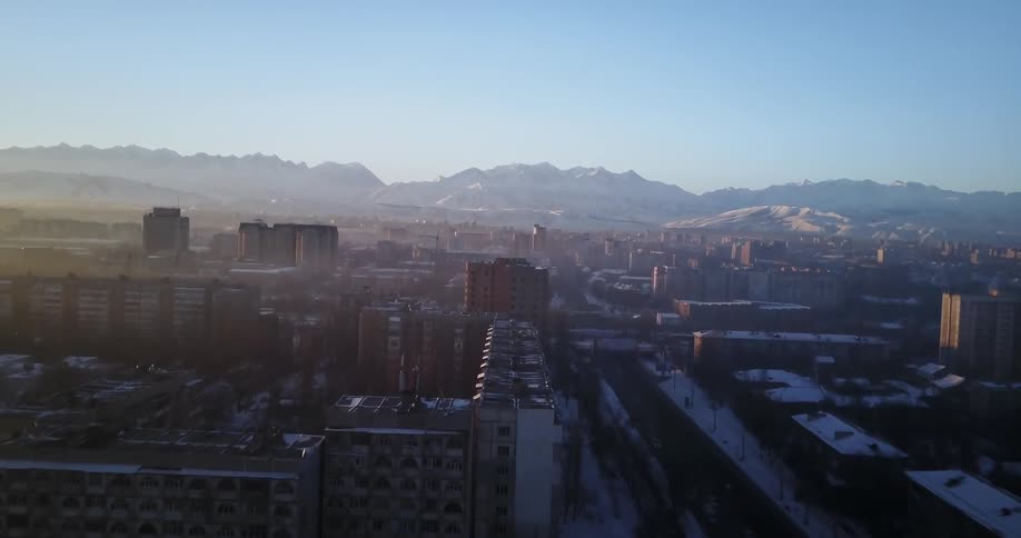 Snow covers city buildings at sunset