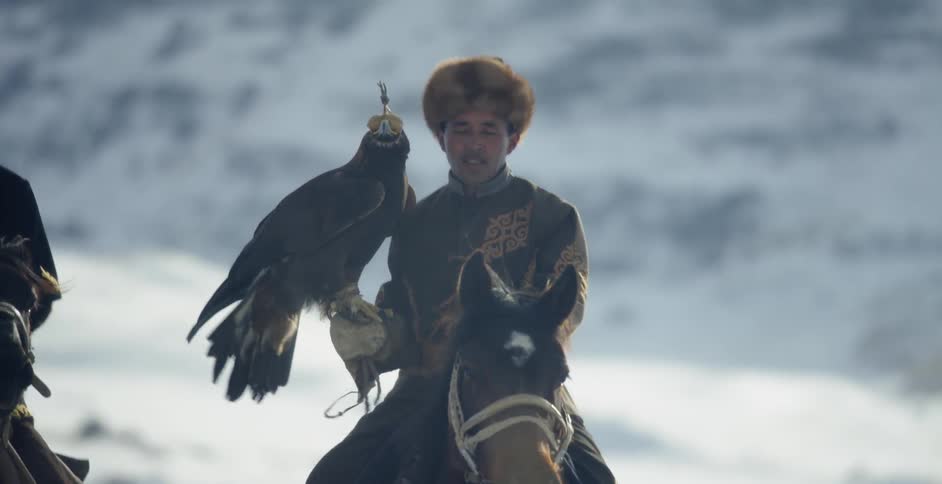 Men ride on horses while holding large birds