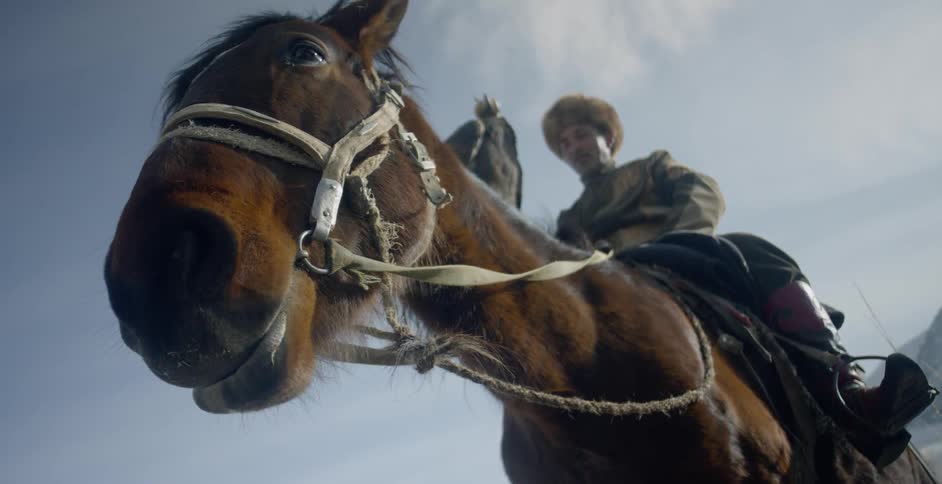 A man rides outside on a horse on a cloudy day