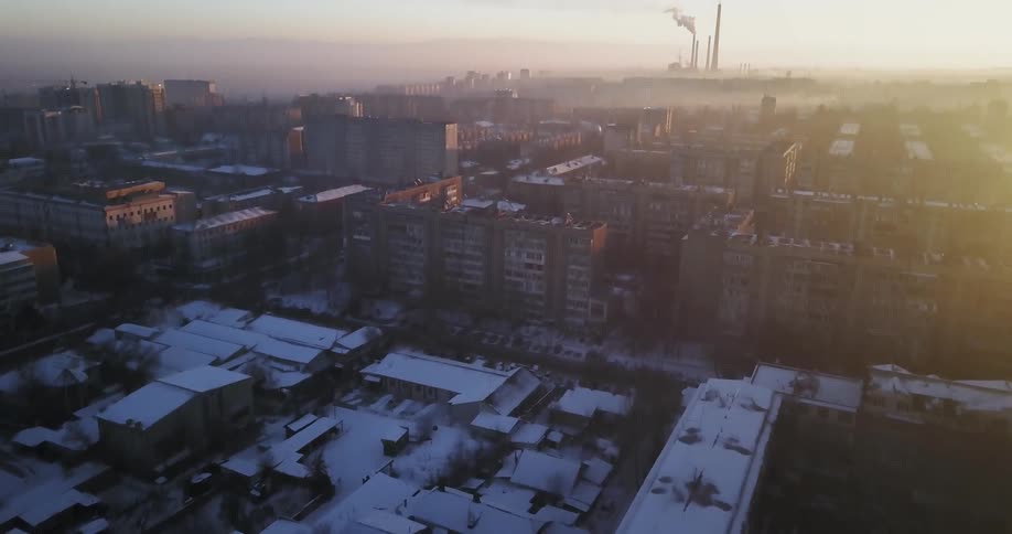 Snow covers city buildings at sunset