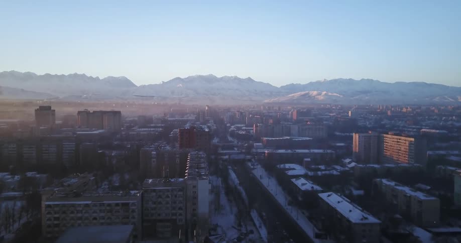 Haze is settling in the air over a city in a mountain valley during a winter day