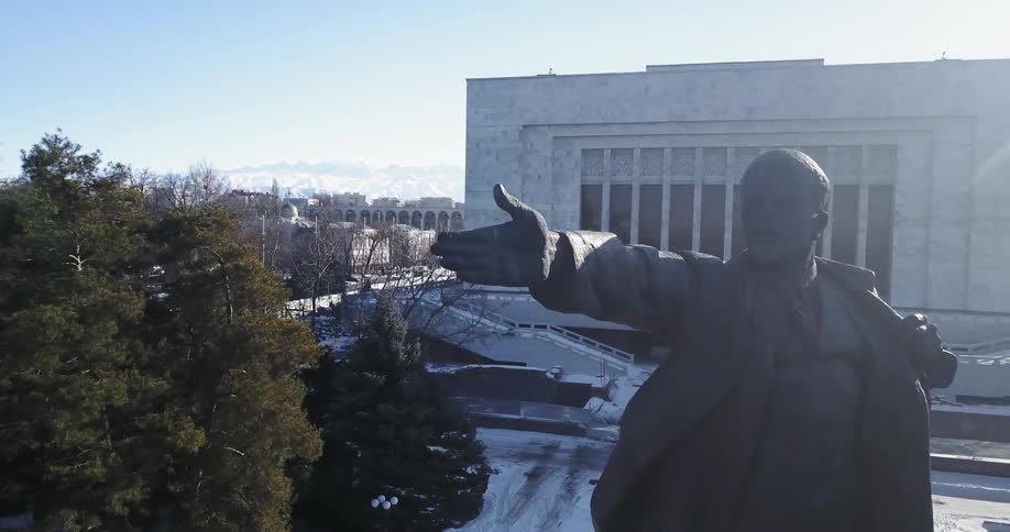 A statue of lenin dominates a public square on a winter day