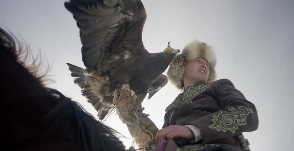 Man holds large bird as he sits on a horse