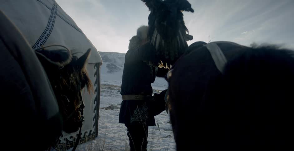 Person gets off of a horse while holding a large bird
