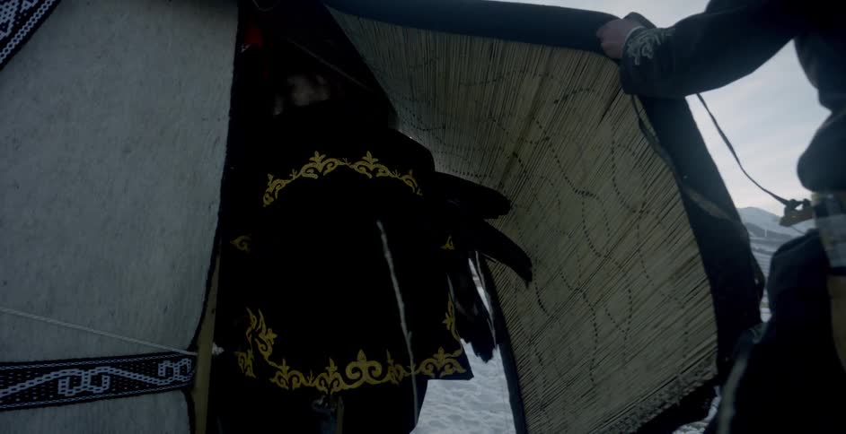 A man holds the tent flap open for another both with eagles perched on their arms