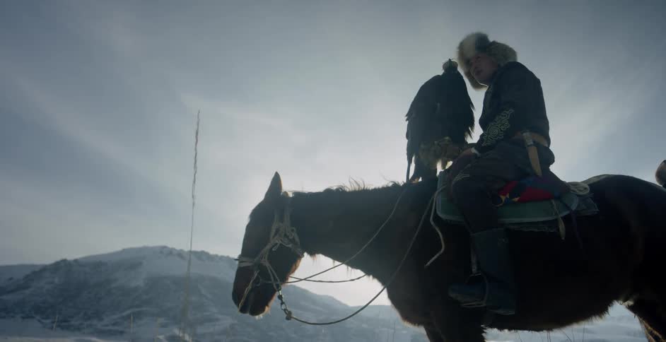 A man rides a horse with a golden eagle