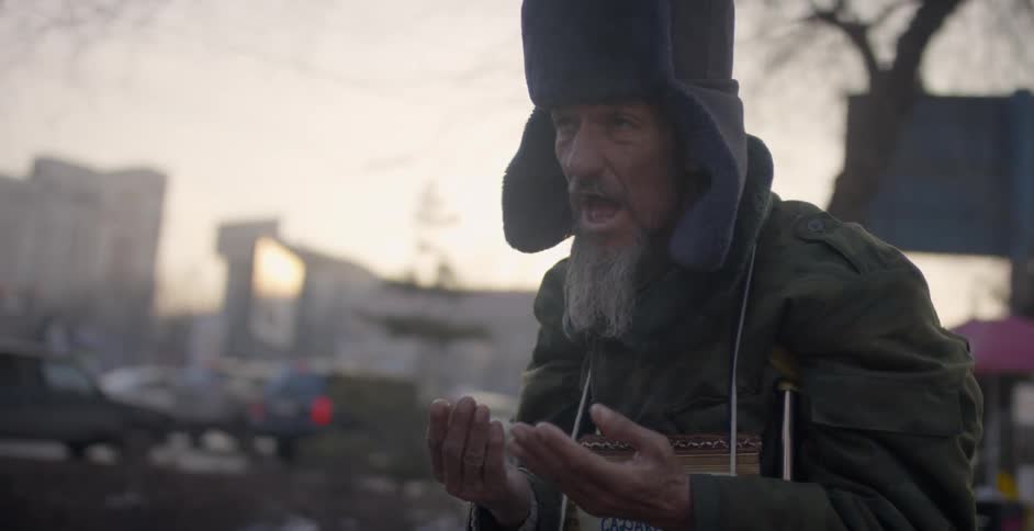 Man talks while wearing a sign and covers his face with his hands