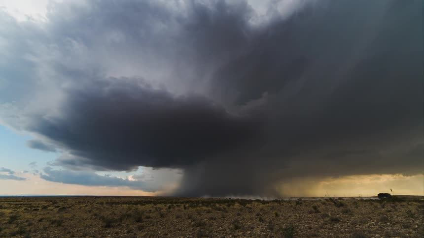 Timelapse view of clouds rolling in over a desert plain, with some of the clouds meeting the ground in the far distance