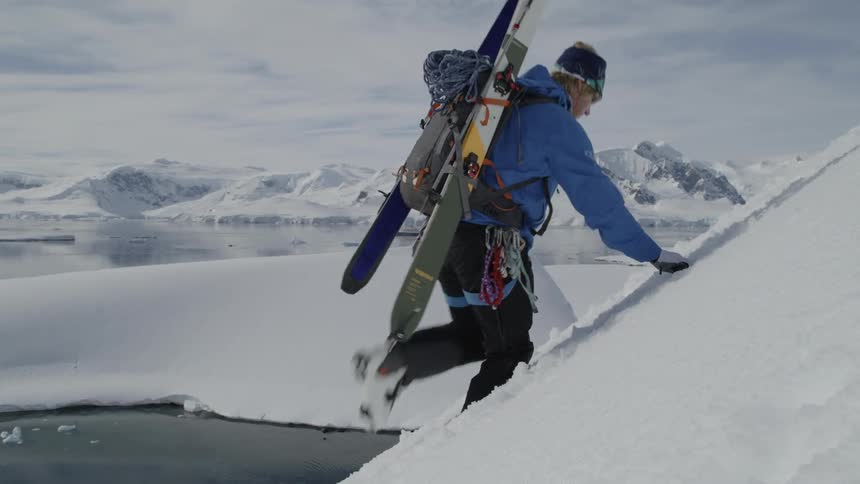 A skier climbs up a snowy mountainside