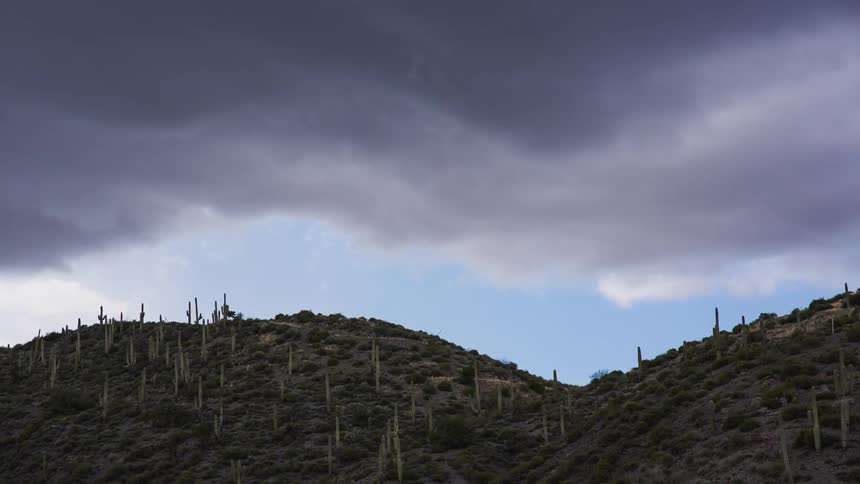 Timelapse of churning rain clouds above a hilly landscape