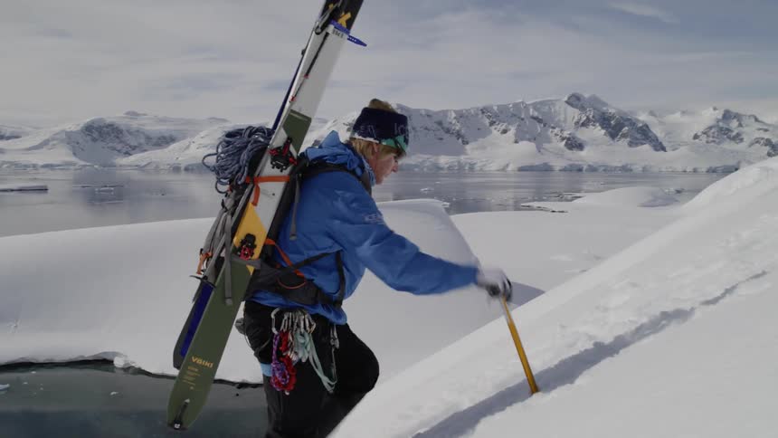 A person is hiking up the slope with skis on his back