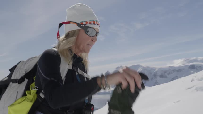A woman hikes in the snow with skis