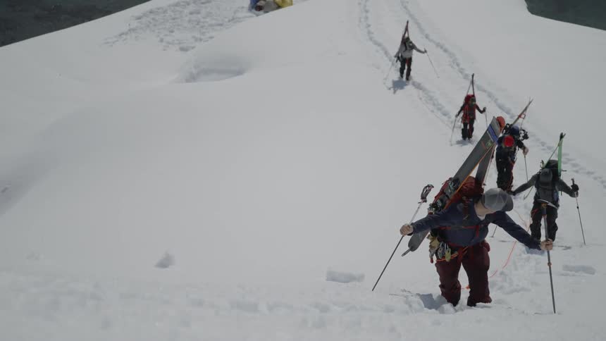 Skiers hike up a snowy mountainside