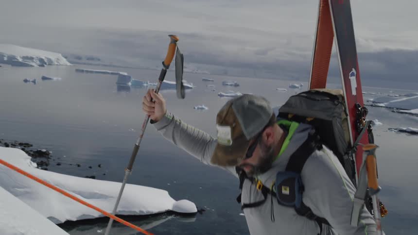 A man slowly climbs up the slope with poles