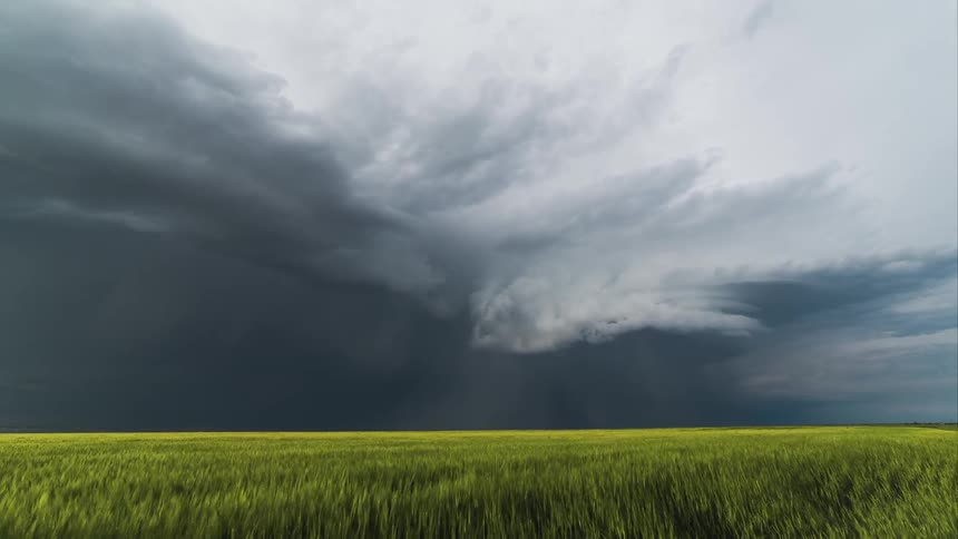 Time lapse of a large grass field as a storm forms