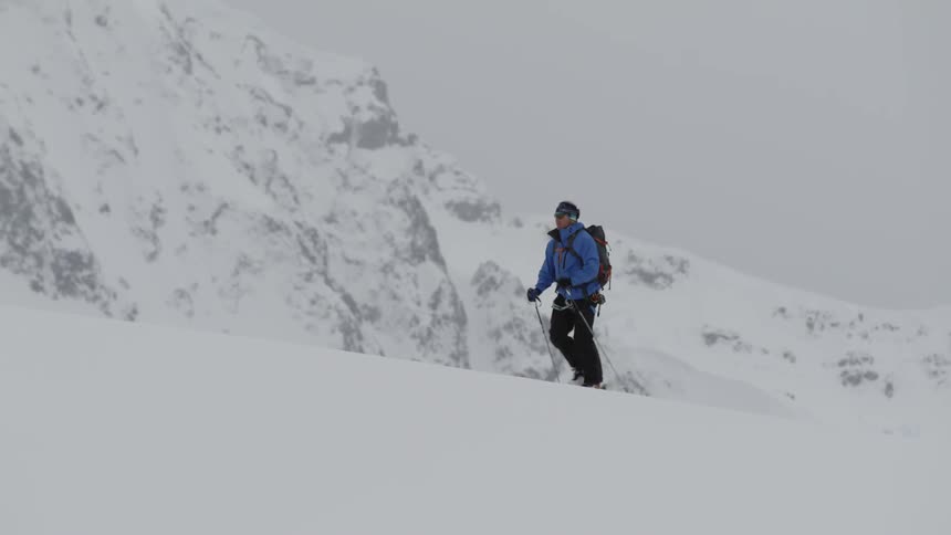 A skier hikes up a snowy mountainside